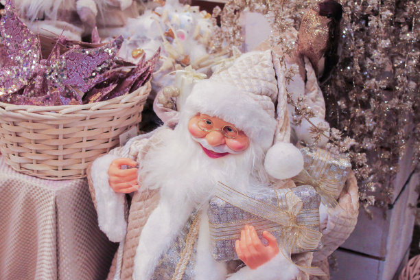 华丽的淡粉色和白色圣诞装饰品:圣诞老人的特写，闪亮的鲜花，蝴蝶和礼物。豪华的圣诞图片下载