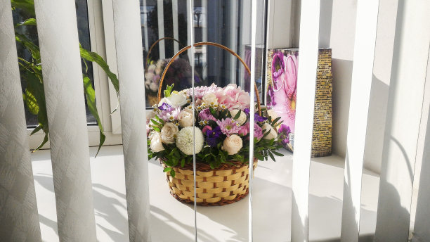 窗帘后面的窗台上有一个篮子，里面装着一束漂亮的鲜花图片下载