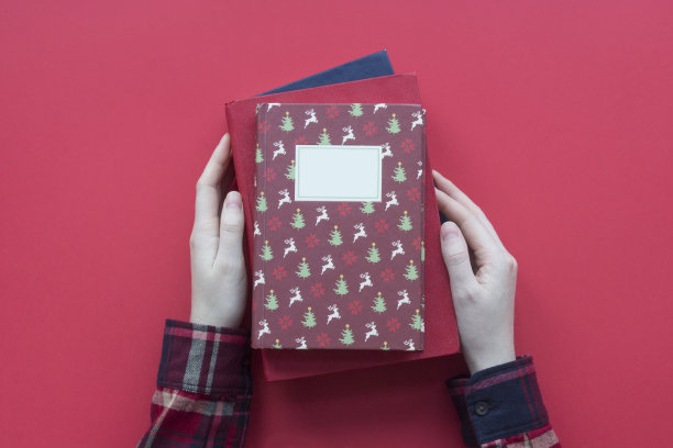 女人的手在一件衬衫拿圣诞书在红色背景俯视图图片下载