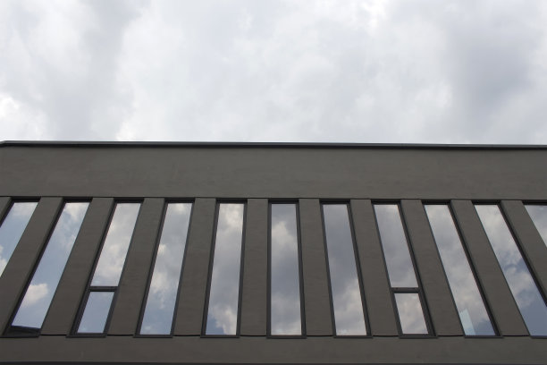 现代建筑的底部视图和它的窗户反映天空中的云。图片下载