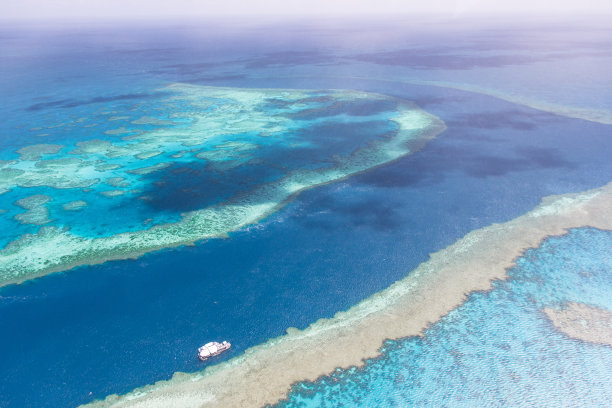 鸟瞰海峡与水肺潜水旅游船通过大堡礁附近的airlie海滩被浅水珊瑚礁包围在蓝绿色的清澈的水。图片下载