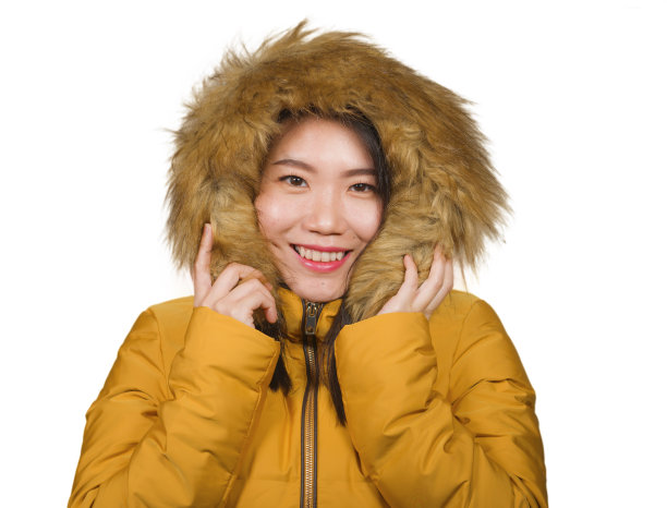 冬季时尚孤立的年轻美丽和快乐的亚洲韩国女人的肖像在温暖的黄色羽毛夹克毛皮兜手势愉快和顽皮的微笑与甜蜜的面部表情图片下载