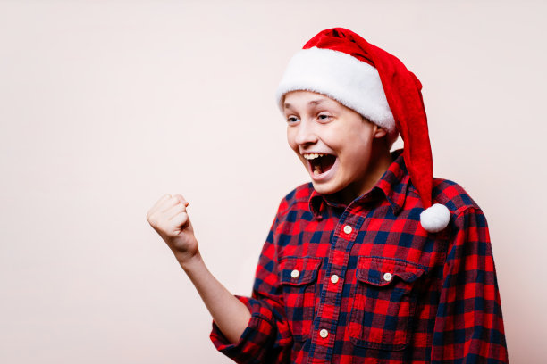 兴奋的男孩在圣诞帽做出胜利的手势图片下载