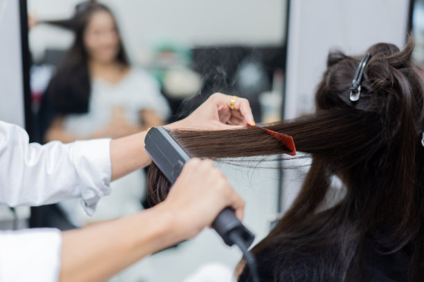 在美容院给顾客熨头发的美容师图片下载