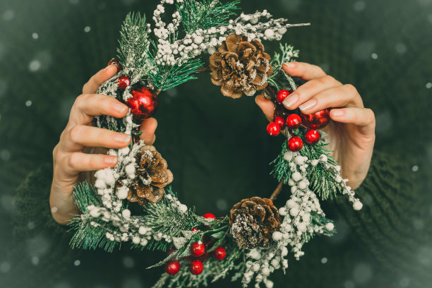 松树花环和圣诞节装饰在女性的手在绿色针织背景。圣诞节，新年，准备过节图片下载