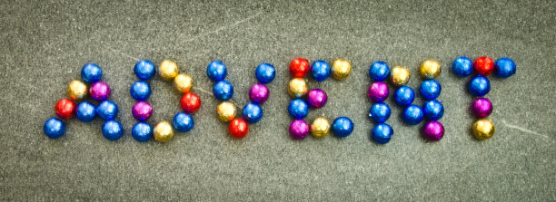 “降临”一词平铺在地上，子弹般的巧克力在金色、蓝色和红色中闪闪发光图片下载