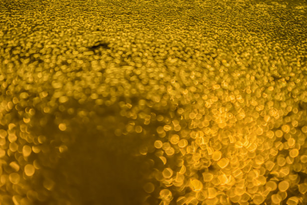 清澈的白色水滴与金色的光的抽象图案，就像酒精啤酒表面的深色，照片的概念为闪光的散景背景与复制空间的文本输入图片下载