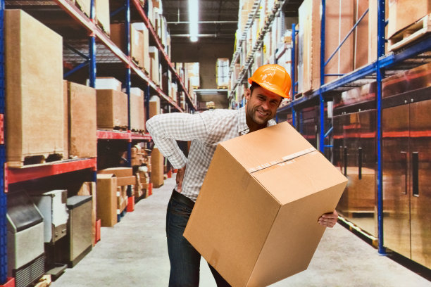 一人/一人/腰部以上/年轻人的正面照片手工工人/摄影站立/弯腰/身体伤害在仓库/配送仓库/工厂/储物柜/仓库前的商品图片下载