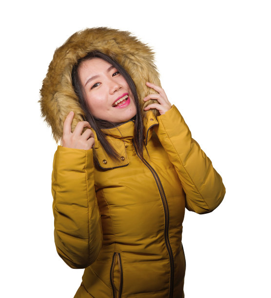 冬季时尚孤立的年轻美丽和快乐的亚洲韩国女人的肖像在温暖的黄色羽毛夹克毛皮兜手势愉快和顽皮的微笑与甜蜜的面部表情图片下载