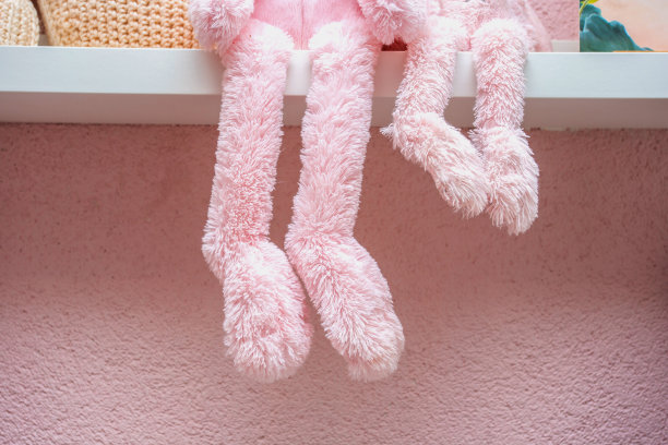 部分毛绒玩具放在粉红色的房间里，粉红色毛茸茸的动物腿挂在女孩房间的白色架子上图片下载