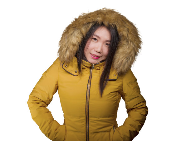 冬季时尚孤立的年轻美丽和快乐的亚洲中国女人的肖像在温暖的黄色羽毛夹克毛皮兜手势愉快和顽皮的微笑与甜蜜的脸表情图片下载
