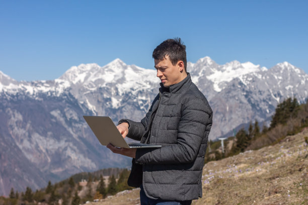一个年轻的自由职业者在山里用笔记本电脑图片下载