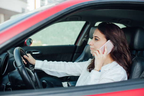 年轻女子坐在车里打电话。库存图片图片下载