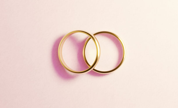 浅粉色背景上的金婚戒图片下载