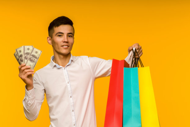 年轻的亚洲人展示他的购物袋和钱图片下载