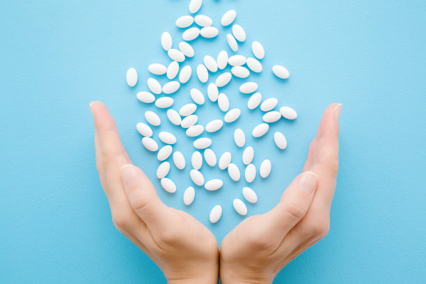 女人手里拿着白色药丸。服用维生素或药物。医疗、制药和保健理念。视角拍摄。特写镜头。浅蓝色背景。自顶向下的观点。图片下载
