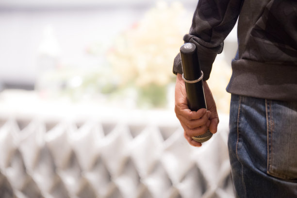 在后台拿着麦克风给会议室里的演讲者图片下载