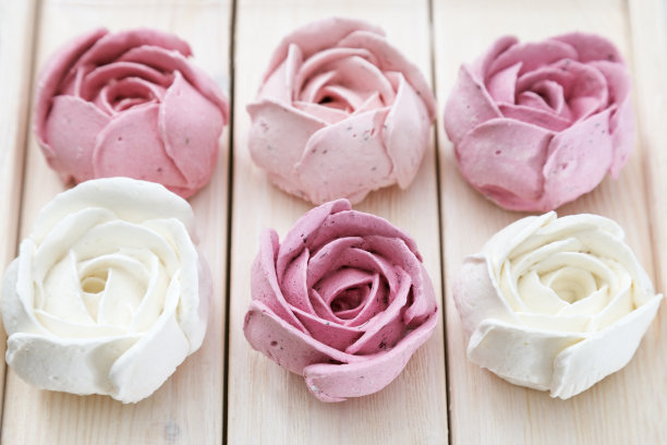 漂亮美味的甜点。木纹表面的花状蛋白酥。蛋白糖霜白色和粉红色的玫瑰的形式。贝瑞zefir。图片下载