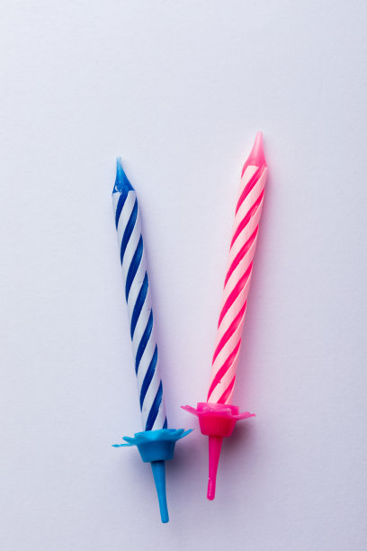2支生日蜡烛，白色背景。生日贺卡。用于插入文本的空格。色彩非常丰富，有蓝色、红色、黄色和白色。生日贺卡。图片下载