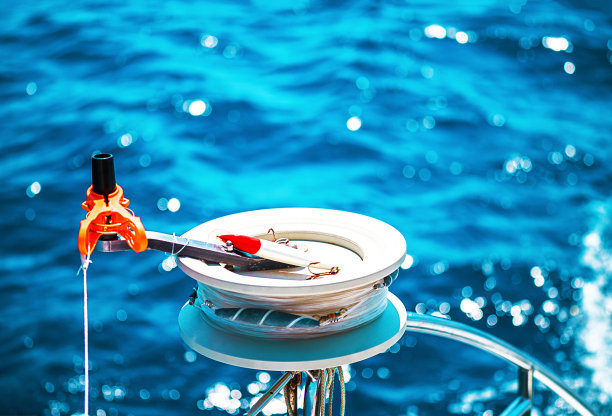 鱼竿卷筒或钓竿卷筒、钓竿。帆船双体船在希腊，雅典附近的爱琴海碧绿水域。图片下载