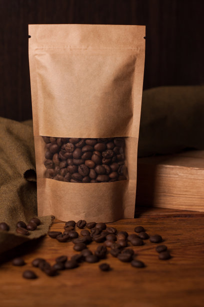 空白的棕色牛皮纸纸袋与咖啡豆在透明的窗户上的木制背景。时尚的茶叶包装图片下载