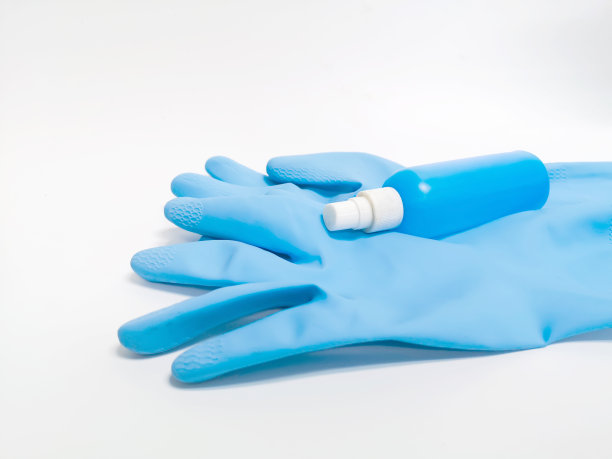 蓝色橡胶手套，白色背景上装有清洗液瓶。家的概念图片下载