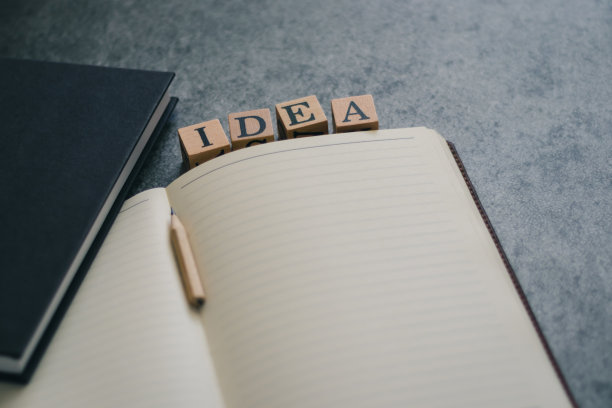 明亮的字母IDEA木方块在笔记本上的照片，铅笔在黑色的背景和复制空间。积极的商业、创新、教育、知识、学习和学习理念。图片下载