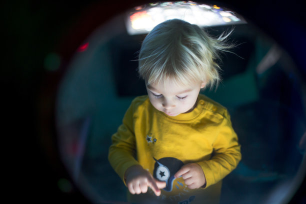 一个蹒跚学步的小男孩在宇宙飞船里，照亮了控制板，孩子在扮演宇航员图片下载