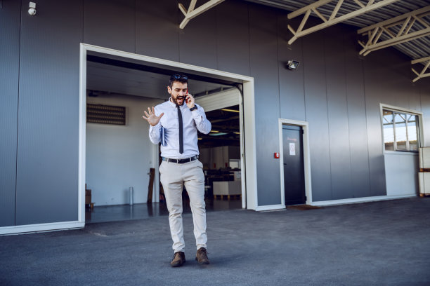 长得帅的白人导演站在打印店前，通过智能手机安排订单。图片下载