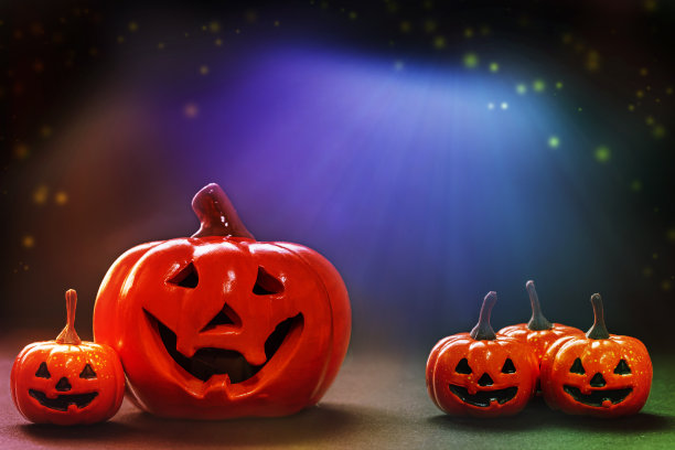 小微笑的橙子和大微笑的南瓜在明亮的，黑色的，多彩的背景上。图片下载