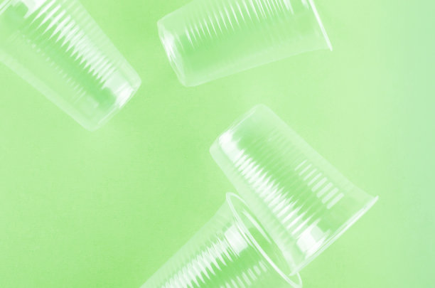 白色一次性杯子，盘子，叉子，刀在浅绿色背景特写-环境问题的概念图片下载