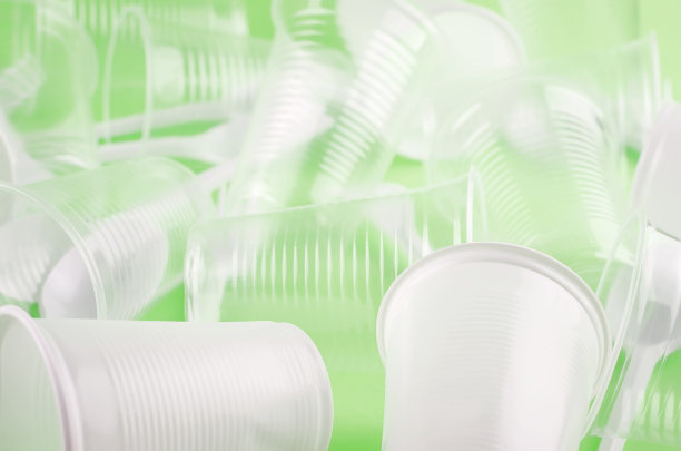 白色一次性杯子，盘子，叉子，刀在浅绿色背景特写-环境问题的概念图片下载