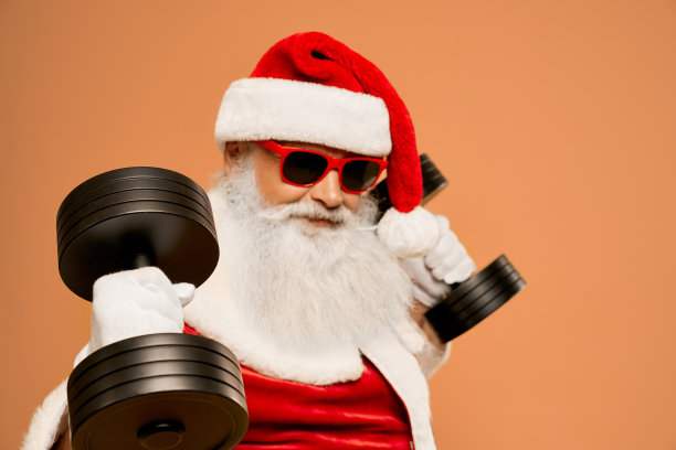 有真胡子的酷圣诞老人用两个哑铃锻炼图片下载