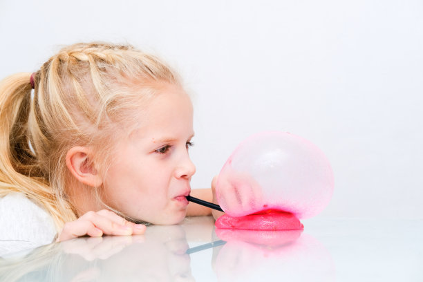 金发女孩正在用粉红色的闪光黏液吹泡泡。泥玩具玩。在家制作黏液图片下载