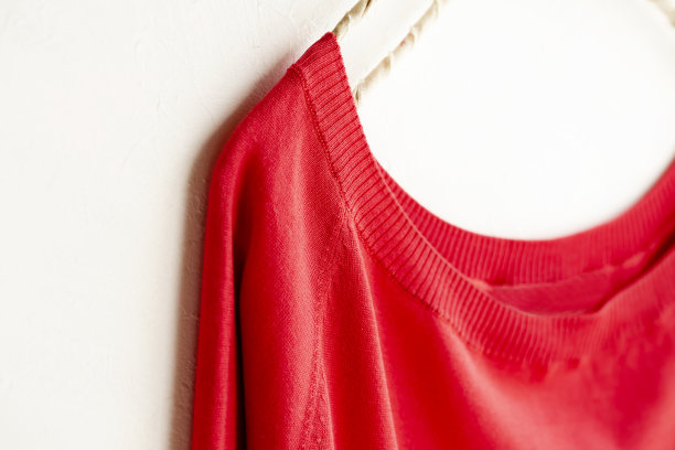 挂在衣架上以白色为背景的红色裁剪的缝纫或编织。图片下载