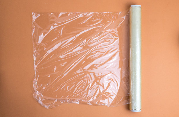 一卷食品薄膜，背景为浅棕色图片下载