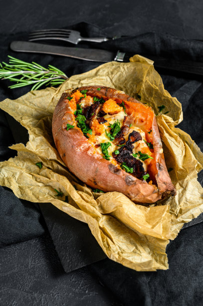 烤甘薯塞满奶酪和培根。黑色背景。空间的文本图片下载