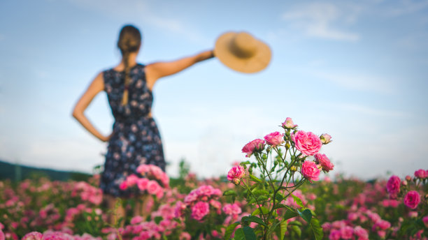 女孩在花后挥舞着帽子图片下载