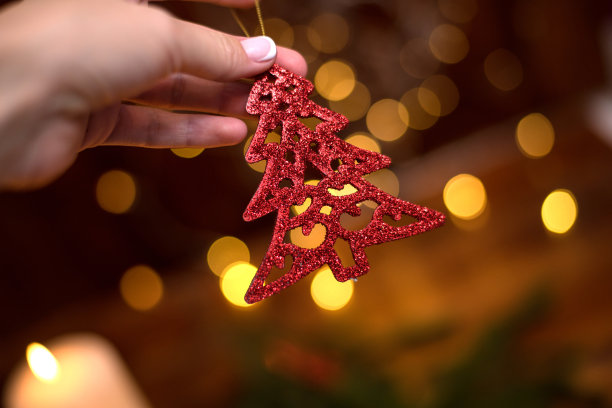 红色装饰圣诞树的树枝在女人手里。背景是散景。圣诞贺卡图片下载