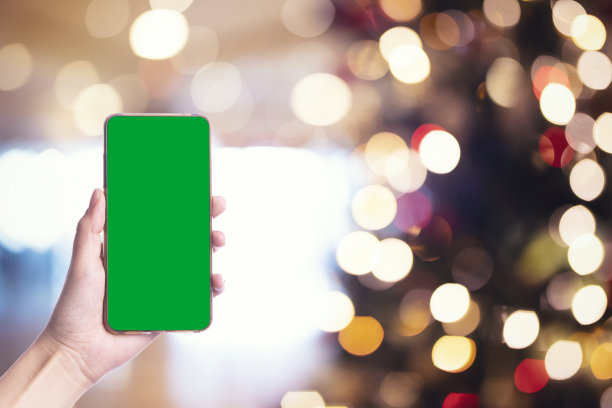 手持手机与Chroma绿色和圣诞节图片下载