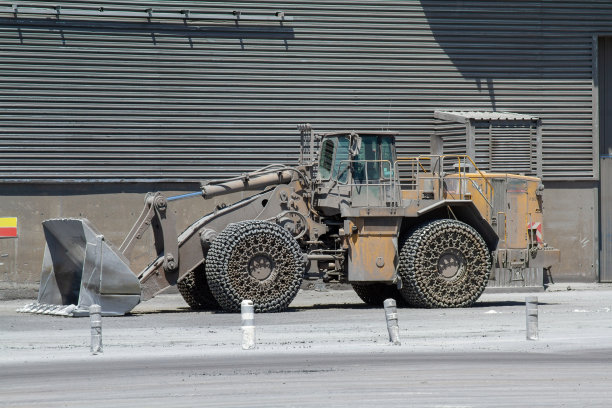 尘土飞扬的黄色推土机停在航站楼灰色的墙壁附近图片下载