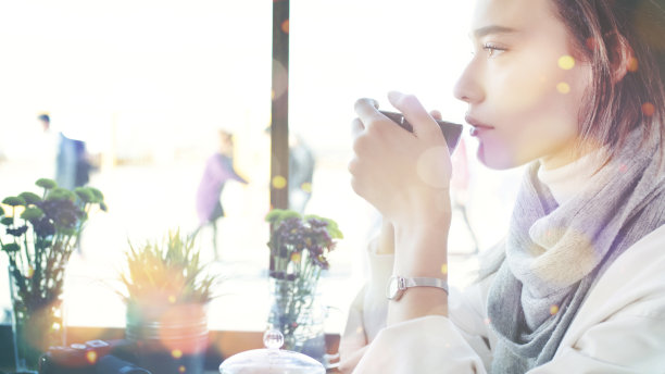 侧面的漂亮迷人的女人肖像与咖啡和圣诞灯bokehs图片下载