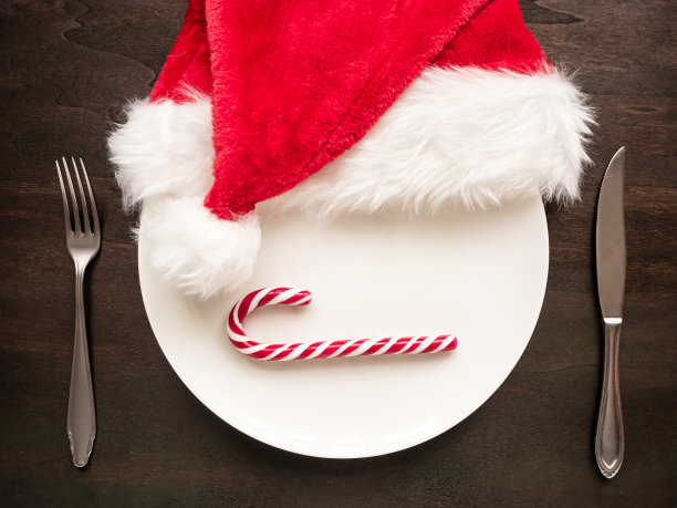 桌上放着拐杖糖和圣诞老人帽的白色盘子图片下载