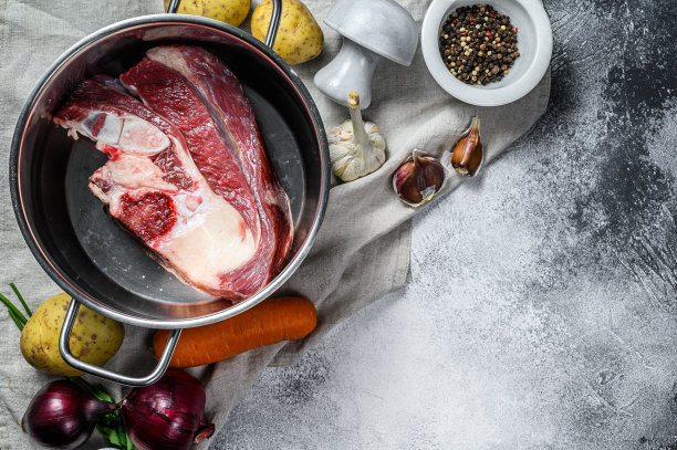 煮锅用骨头煮肉汤。蔬菜，烹饪材料和香料在厨房的桌子上。前视图。空间的文本图片下载