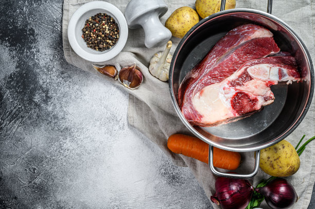 煮锅用骨头煮肉汤。蔬菜，烹饪材料和香料在厨房的桌子上。前视图。空间的文本图片下载