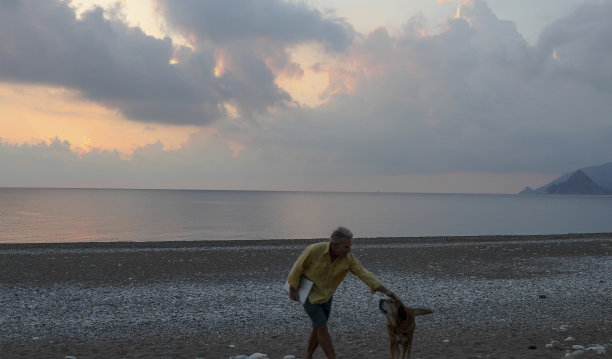 日出时，人们走在空旷的海滩上图片下载