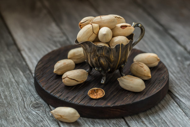 杯子里的山核桃(薄壳山核桃)洒在一个木制背景特写上图片下载