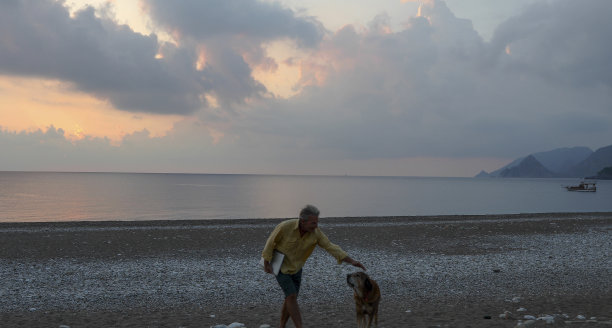 日出时，人们走在空旷的海滩上图片下载