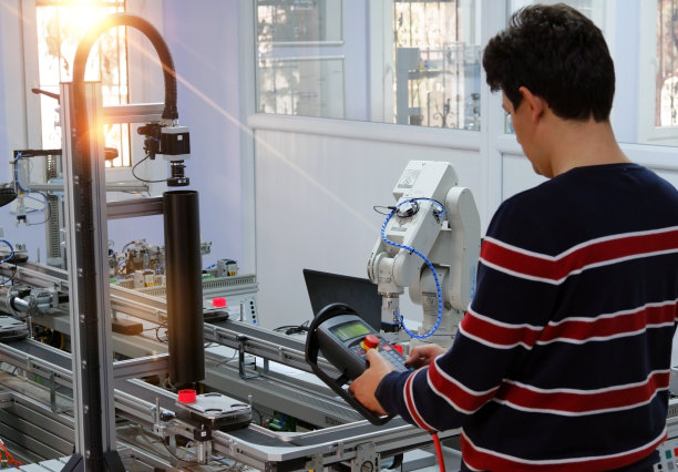 人类正拿着教学面板来控制机械手臂图片下载