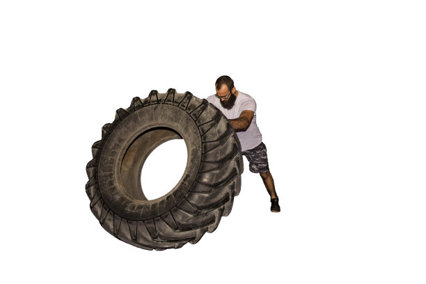 一个年轻的运动员在转动一个大轮胎图片下载